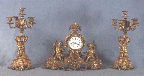 Reloj y dos candelabros de bronce con putinos