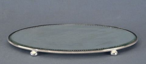 Presentoire oval de metal plateado Epns con espejo, apoya sobre cuatro patas bollo.