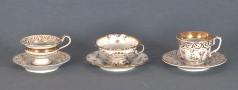 Cuatro tazas con plato de porcelana alemana, distintas, en blanco y dorado