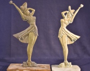 Dos figuras femeninas con sombrero, bases cascaduras. Dos esculturas de bronce dorado. Alto: 42 y 42,5 cm.