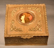 Caja de bronce cincelado con miniatura de esmalte en el centro, faltantes. 10 x 10 cm.