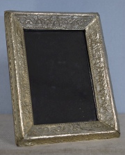 Marco portarretrato de mesa, rectangular de metal repujado. Mide: 19 x 14 cm.