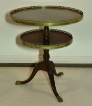 Mesa circular de dos planos; de caoba. Regatones y barandas caladas de bronce dorado. Alto 74 cm. Diám. mayor 64 cm