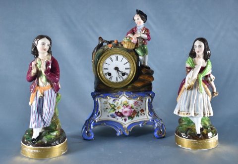 Garniture de porcelana, reloj y dos candeleros con figuras policromadas. (405)