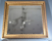 Espejo biselado, con marco dorado con guarda de motivos vegetales. Mide: 100 x 90 cm.
