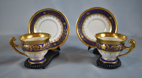 Dos tazas con platos, porcelana blanca con decoracin azul y dorado.