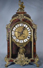 Reloj estilo Boulle, taracea de bronce, mascarn y motivos mitolgicos. Con pndulo y llave. Alto 50 cm.