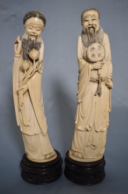 FIGURA CON FLORES y FIGURA CON ABANICO, dos tallas chinas de marfil. Atrás firmadas en rojo. Bases de madera. Alto: 35cm