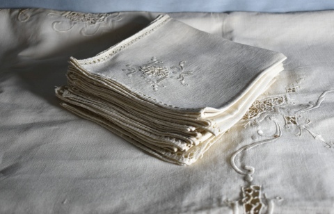 Mantel beige calado, 12 individuales, con manchas. Detalles de bordado. Mide: 260 x 168 cm.