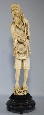 PESCADOR, figura de marfil tallado, con base de madera. Alto: 29,5 cm. Alto total: 34,5 cm.