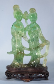 DAMAS PORTANDO ATRIBUTOS, figura de raíz de esmeralda tallada con base de madera. Alto total: 19,2 cm.