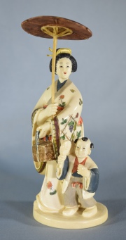 MUJER JAPONESA CON NIÑO Y SOMBRILLA, figura de marfil tallado y policromado. Faltantes. Al dorso firmado. Alto: 15,5 cm.