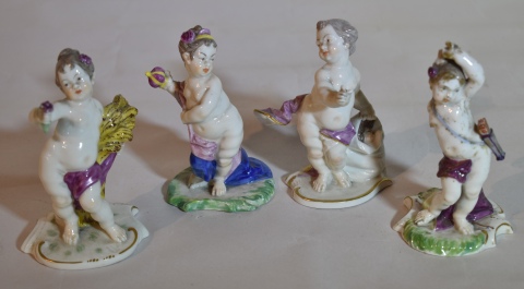 Cuatro putinos de porcelana europea. Uno con restauros y faltantes. 9.5 cm.