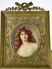 Mujer con flor, placa oval de porcelana esmaltada en marco de bronce dorado. Alto total 24,5 cm.