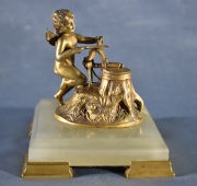 CUPIDO LABARANDO SUS FLECHAS, escultura de bronce dorado con base de mármol onix. Alto: 11 cm.