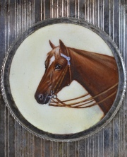 Cigarrera de alpaca con cabeza de caballo en esmalte. Mide: 8,8 x 7,5 cm.