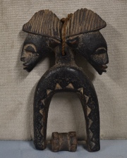 UTENSILIO DE HILAR, talla de madera africana, ornada con dos cabezas. Alto: 18,5 cm.