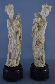 Dos figuras chinas de marfil. Bases de madera calada, una restaurada. Alto total: 31 cm.