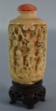 Snuff bottle, chino marfil. Tapa de coral cachada, pegada. Base de madera. Alto: 8,4 cm.